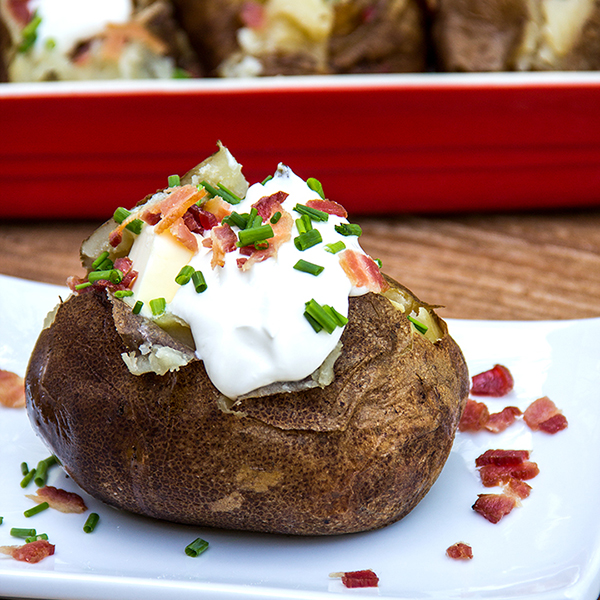 baked potato on a plate with sour cream and bacon