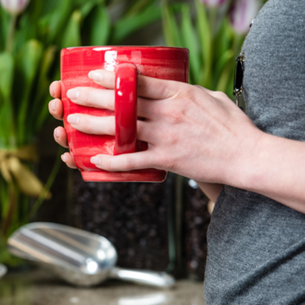 close up photo of a red coffee cup in hands